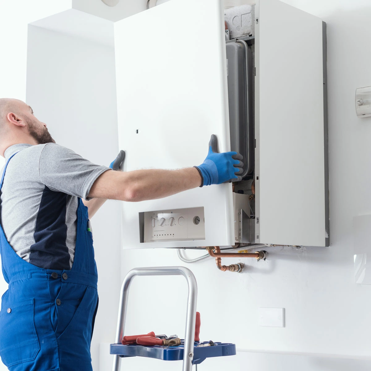 Plumber putting back cover to boiler